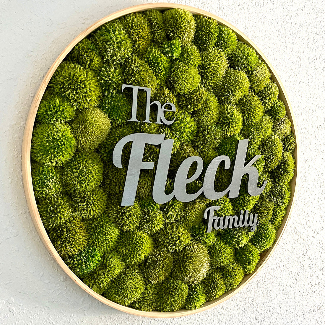 Round preserved moss wall art in a solid wood frame mounted on an interior wall