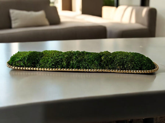 Long gold metal vessel filled with preserved moss running down a conference table