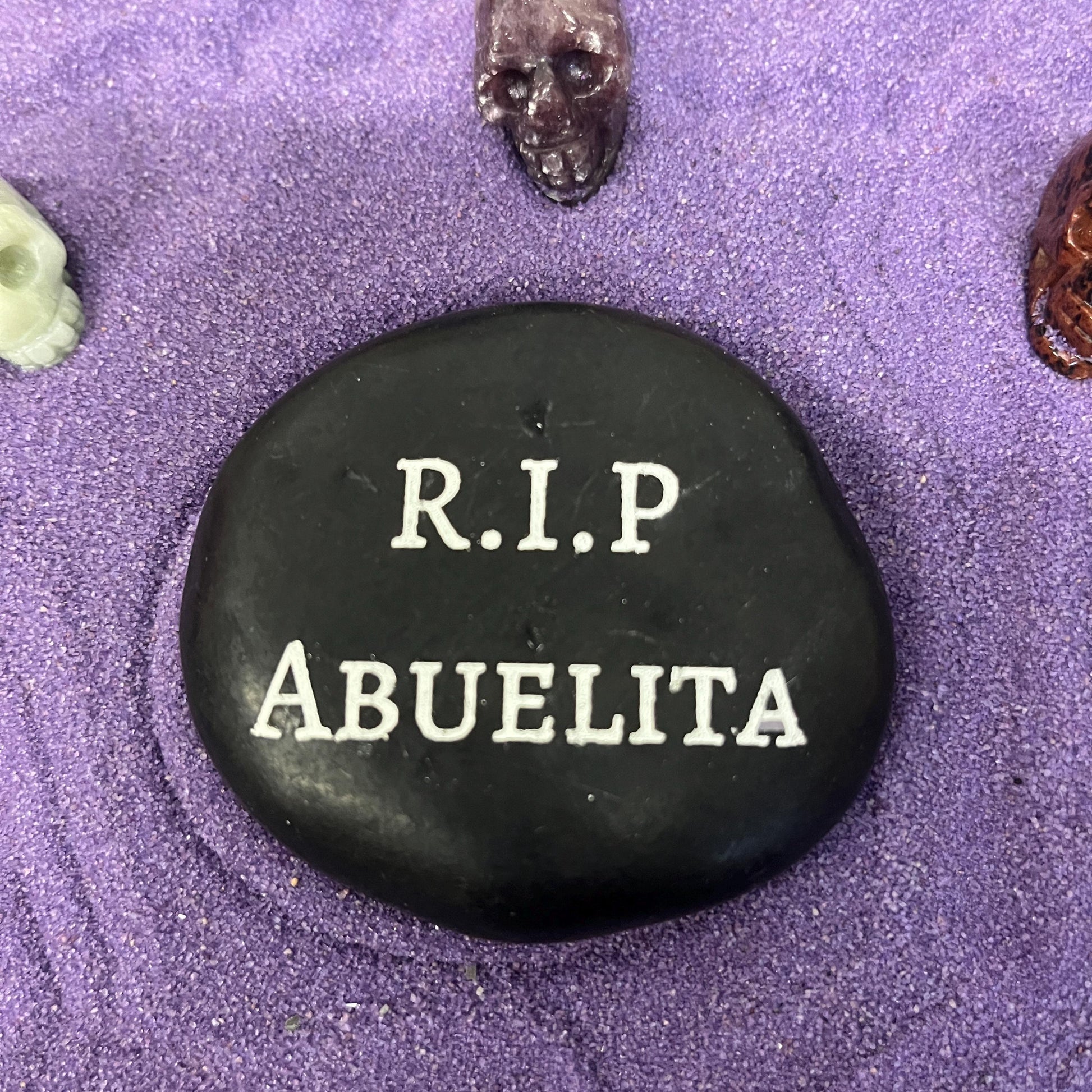 Engraved memorial stone in purple sand with skull figurines